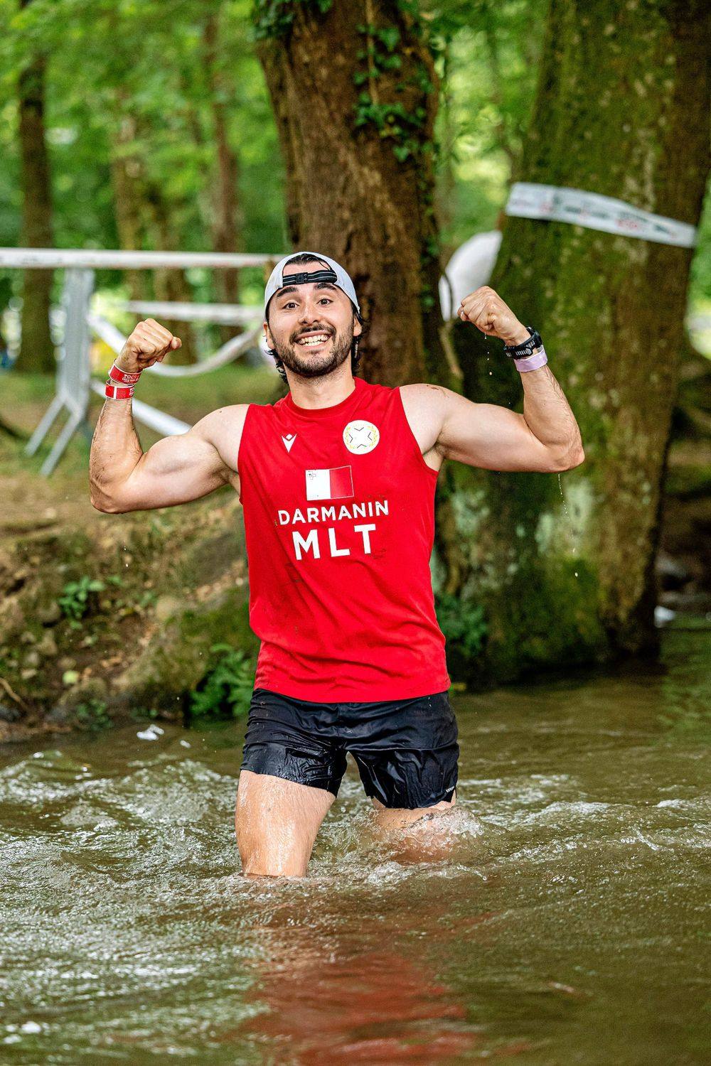 Isaac flexing in a river while racing an obstacle course for Malta